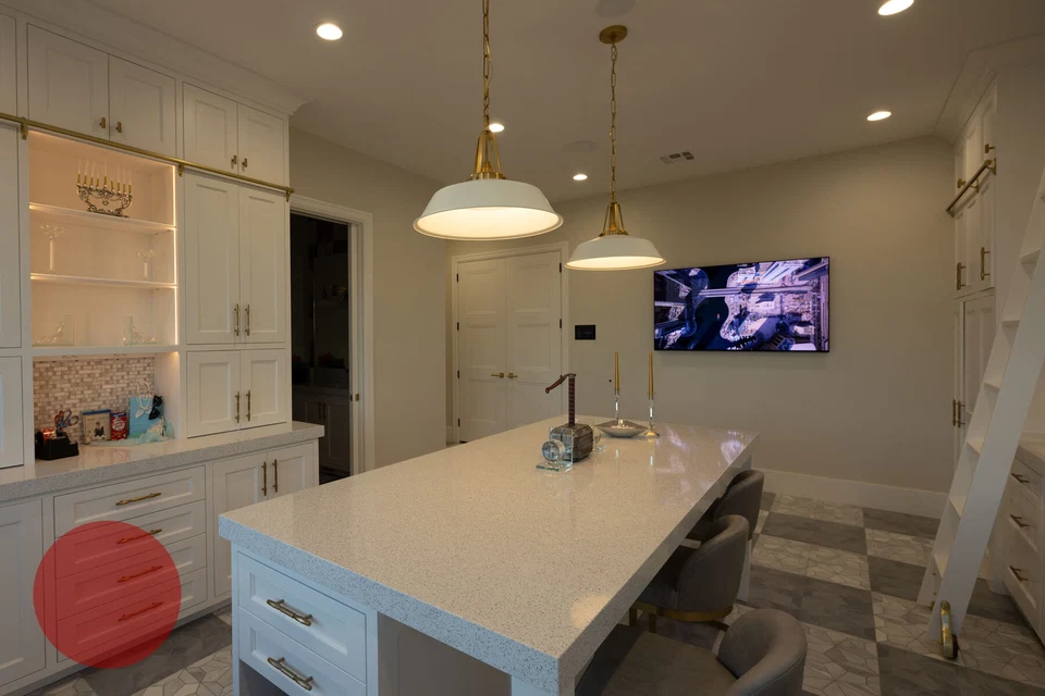White kitchen island facing a wall-mounted television and built-in cabinets