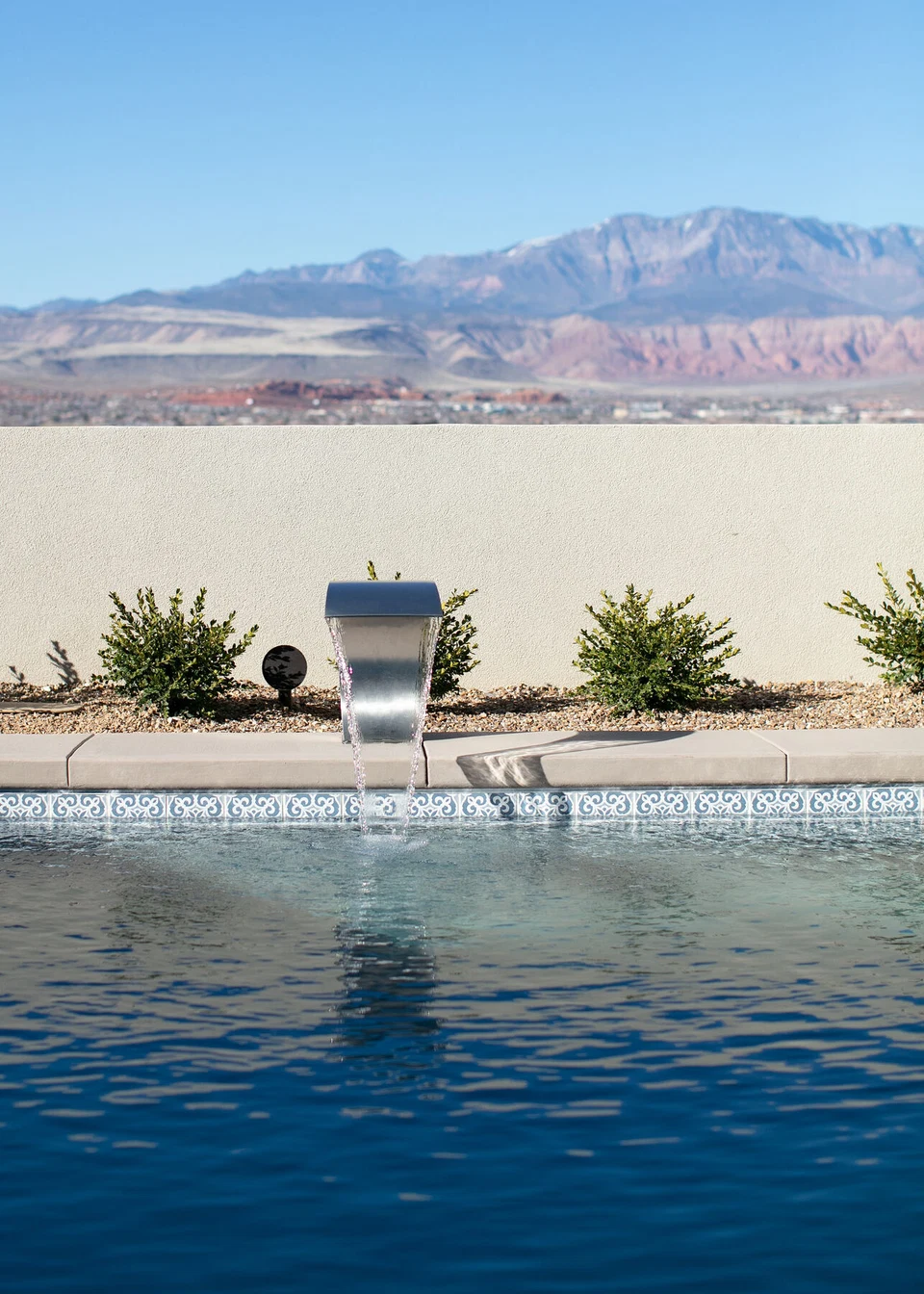 Swimming pool facing a boundary wall and distant red mountains