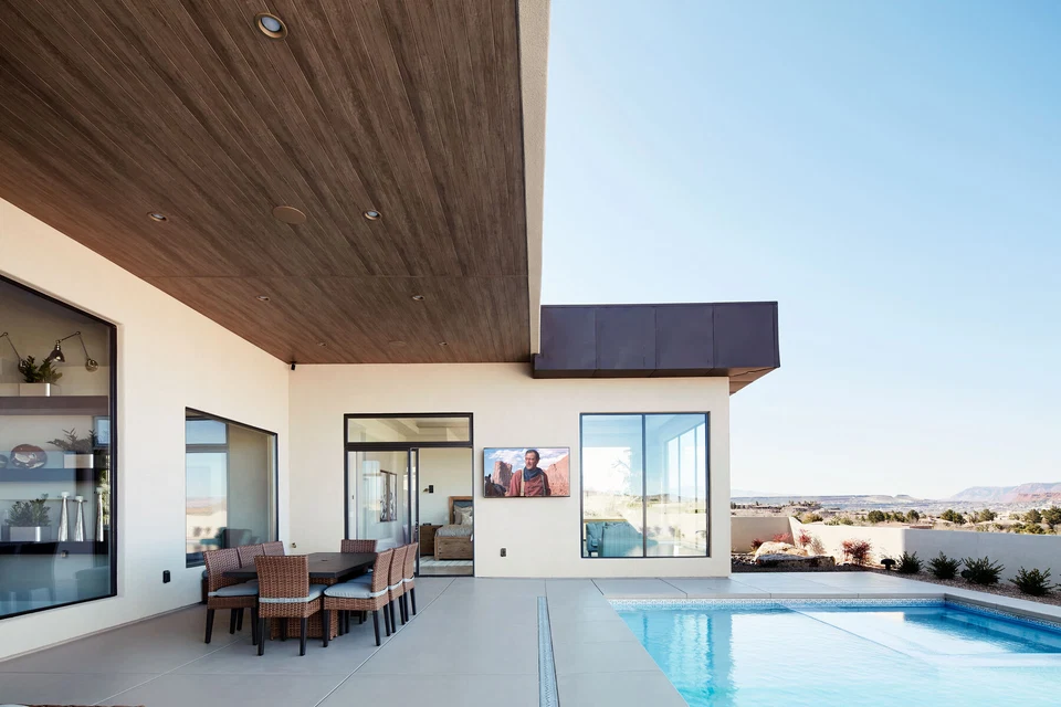 Covered outdoor dining area beside a pool and sliding glass doors