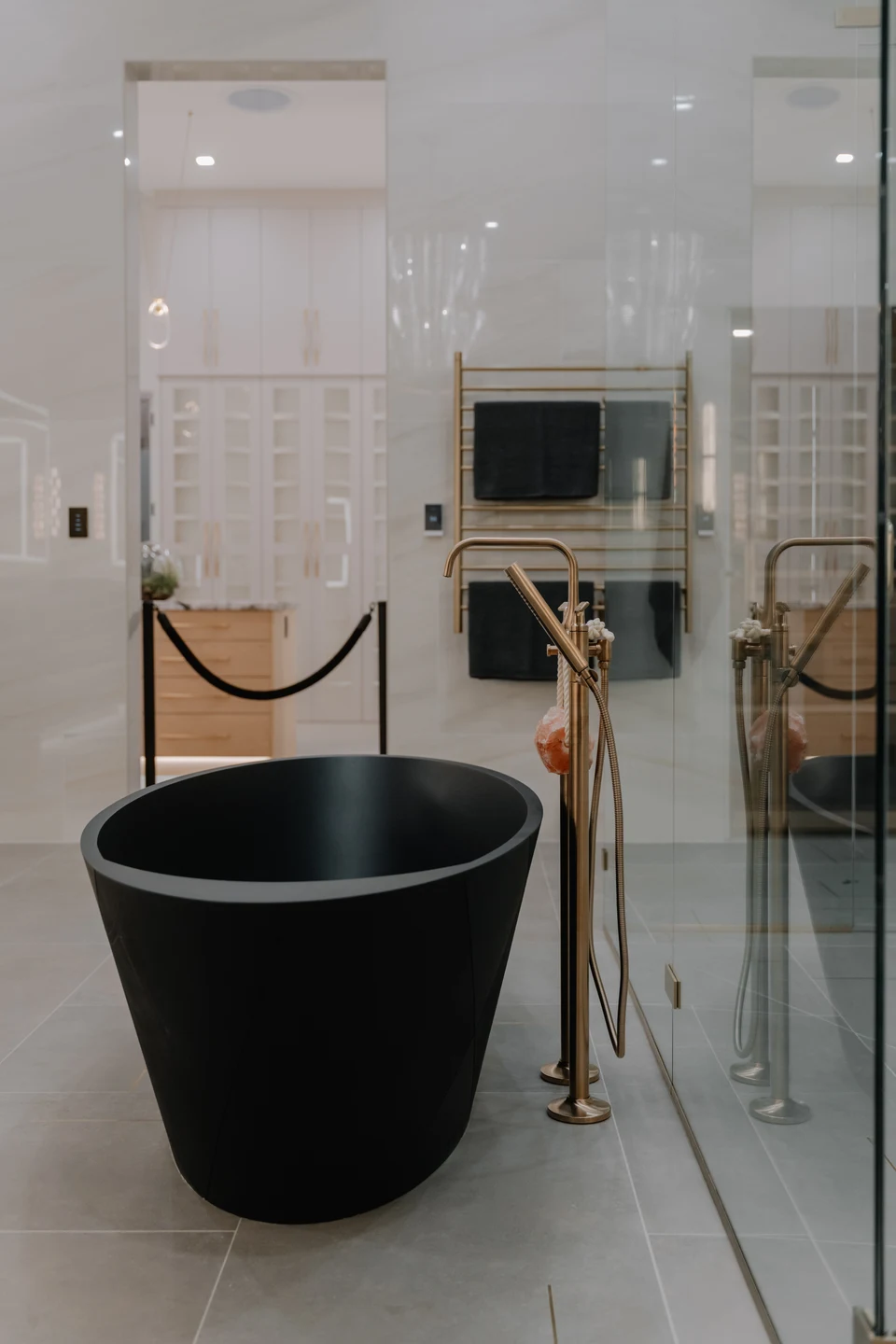 Black bathtub beside a glass shower enclosure and illuminated vanity