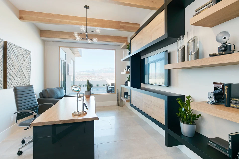 Home office desk facing built-in shelves and a large window