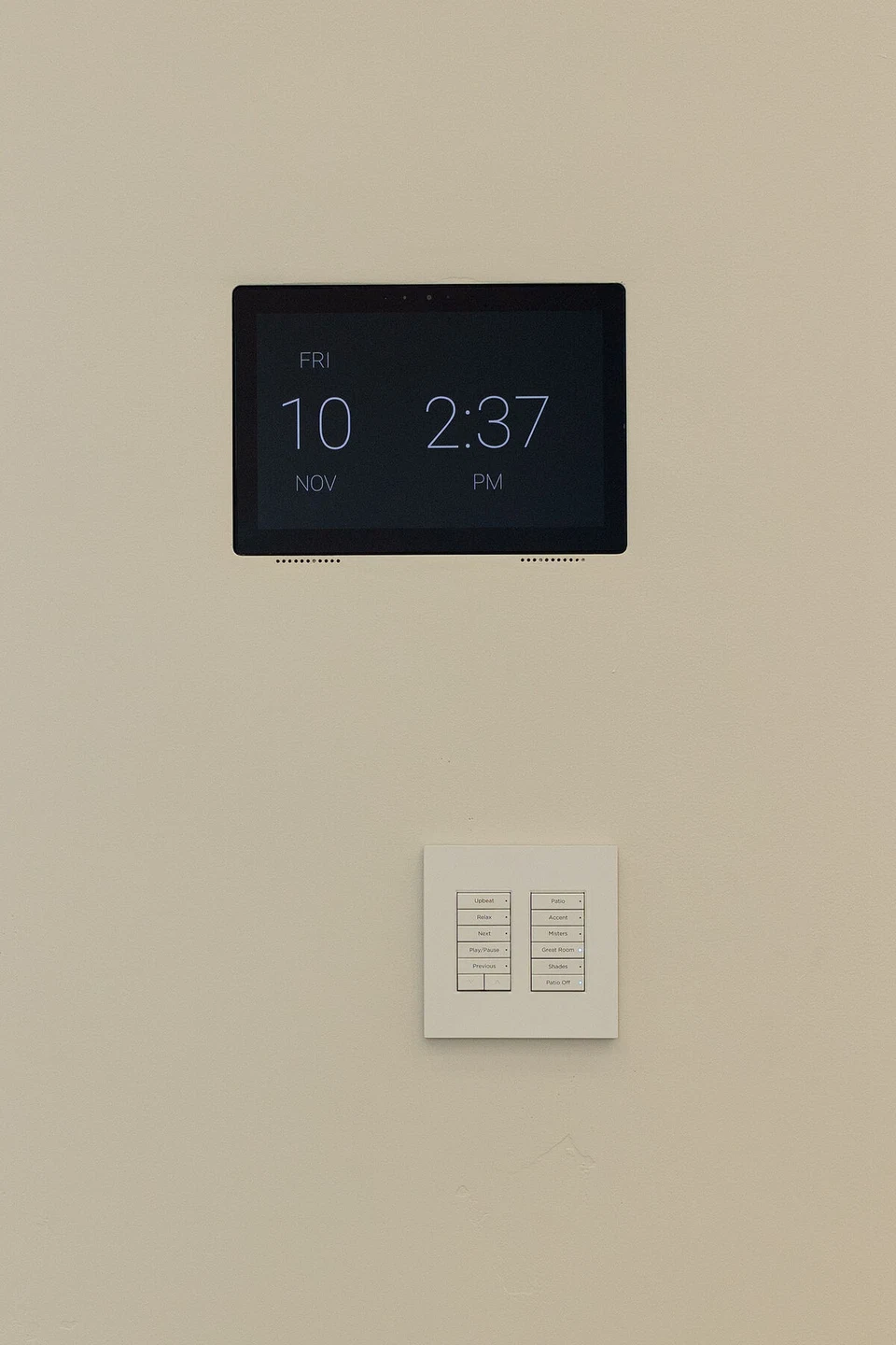 Wall-mounted clock touchscreen above a white lighting keypad