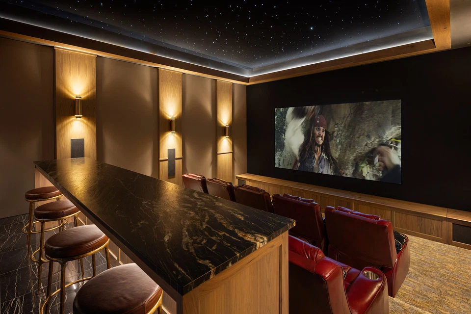 Home theater screen beneath a star ceiling with red seats and a rear counter