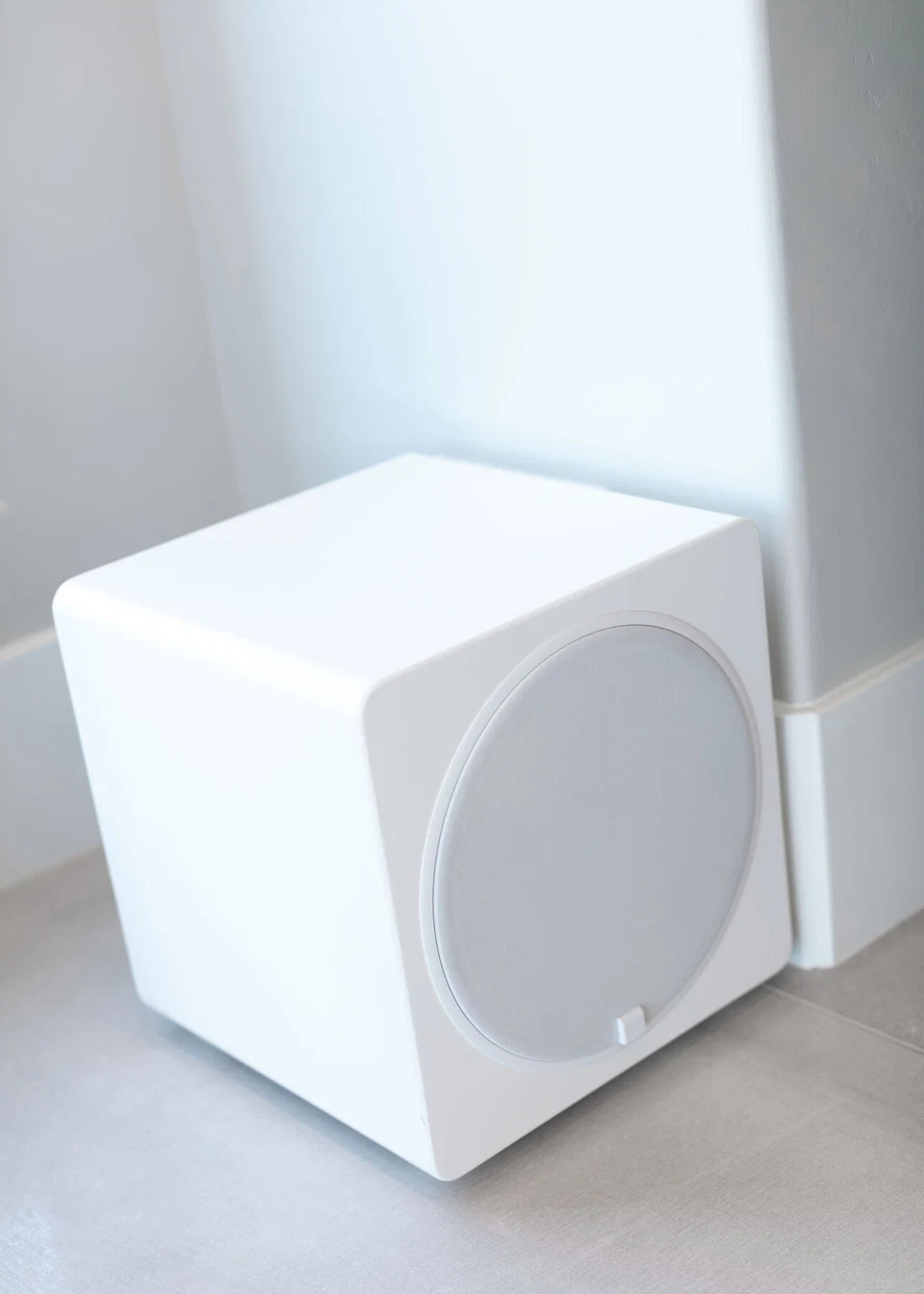 Close view of a white subwoofer with a circular grille