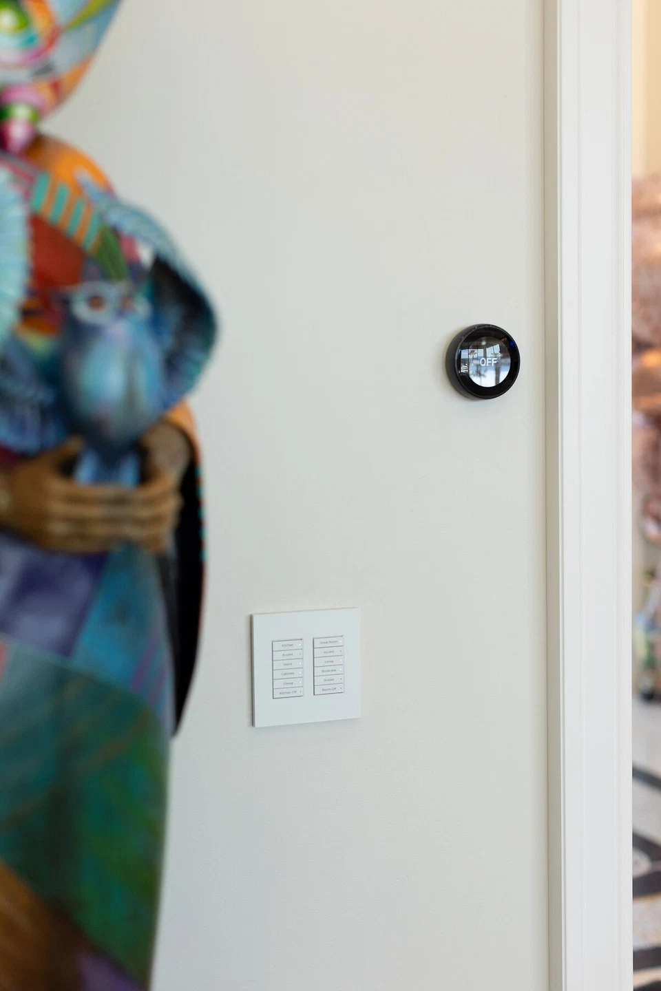 Round black thermostat and white switches beside colorful wall art