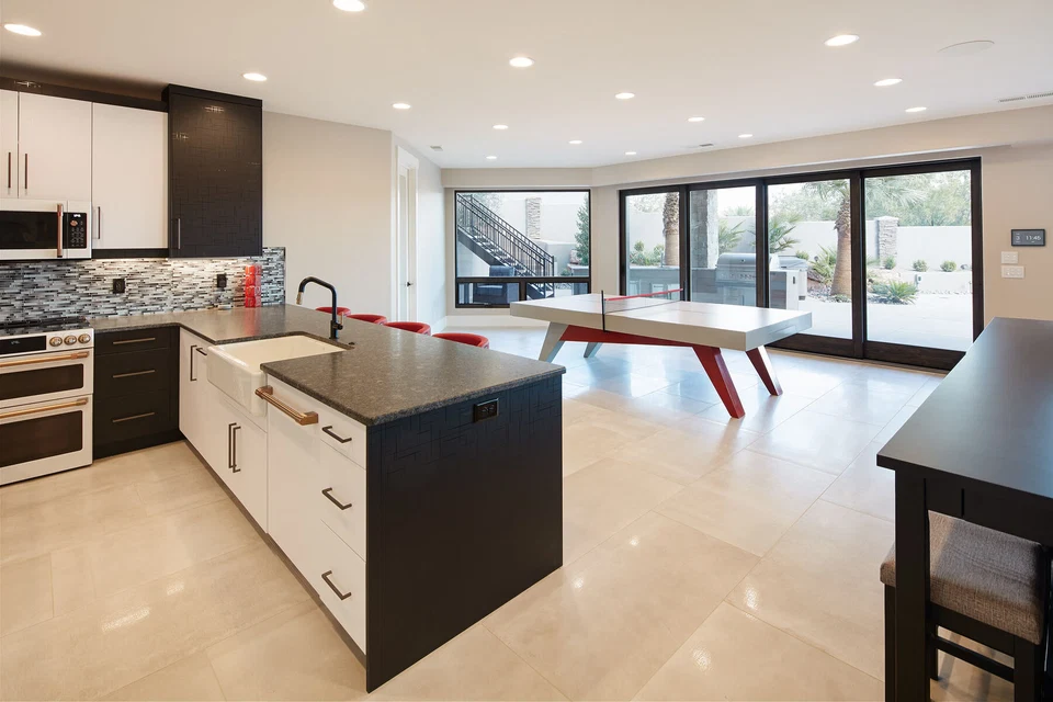 Kitchen island and recreation room beside wide sliding glass doors