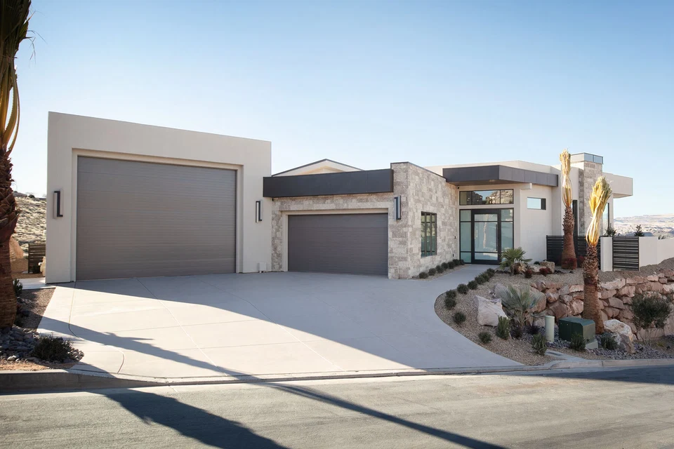 Single-story home with stone entryway, gray garage doors, and desert landscaping