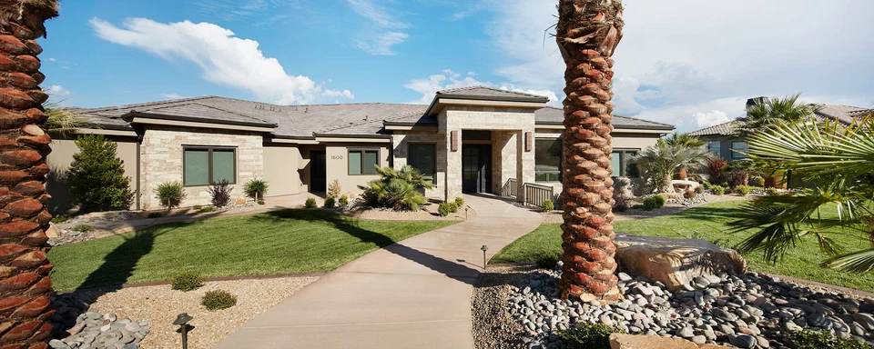 Landscaped front approach to a single-story home with palm trees