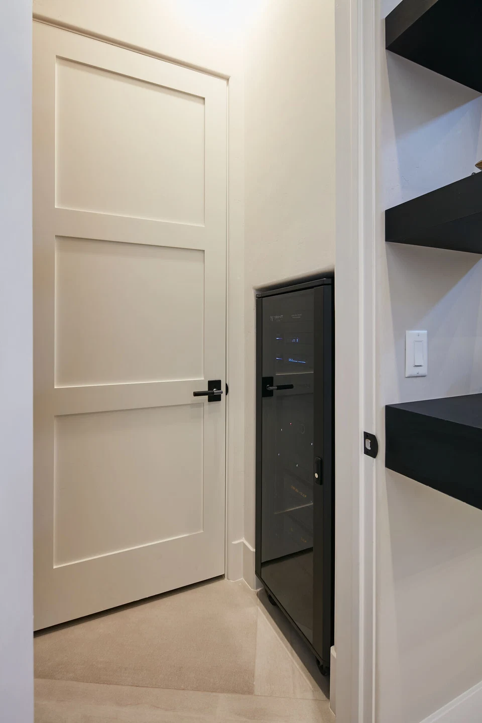 Recessed black equipment panel beside a closet door and shelving