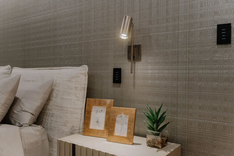 Bedside reading light and two black keypads on a textured wall