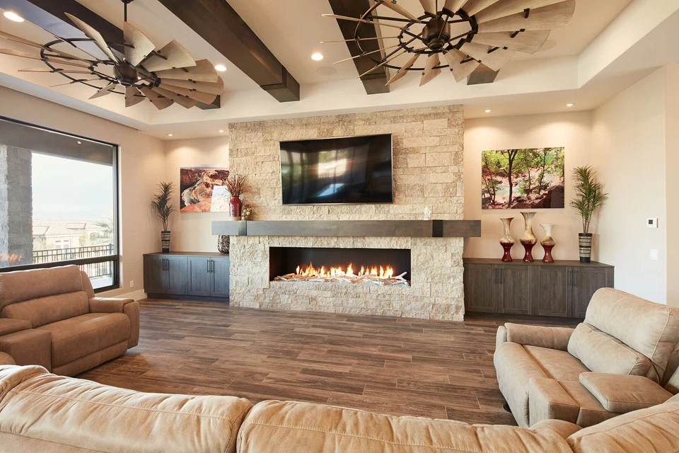 Television above a stone fireplace flanked by dark built-in cabinets