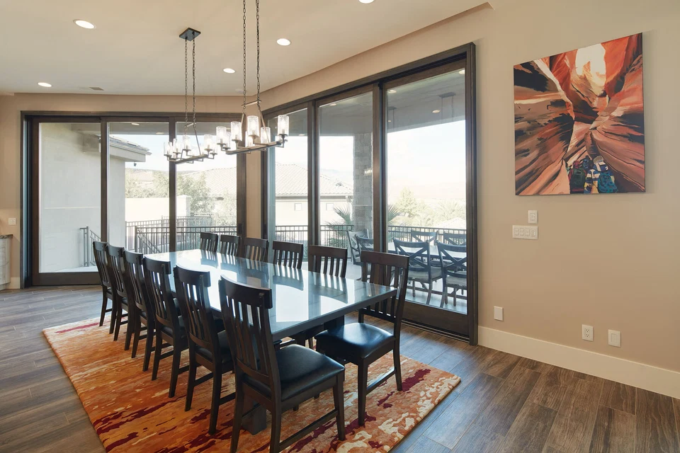 Dining room with window views, dark chairs, and a patterned rug