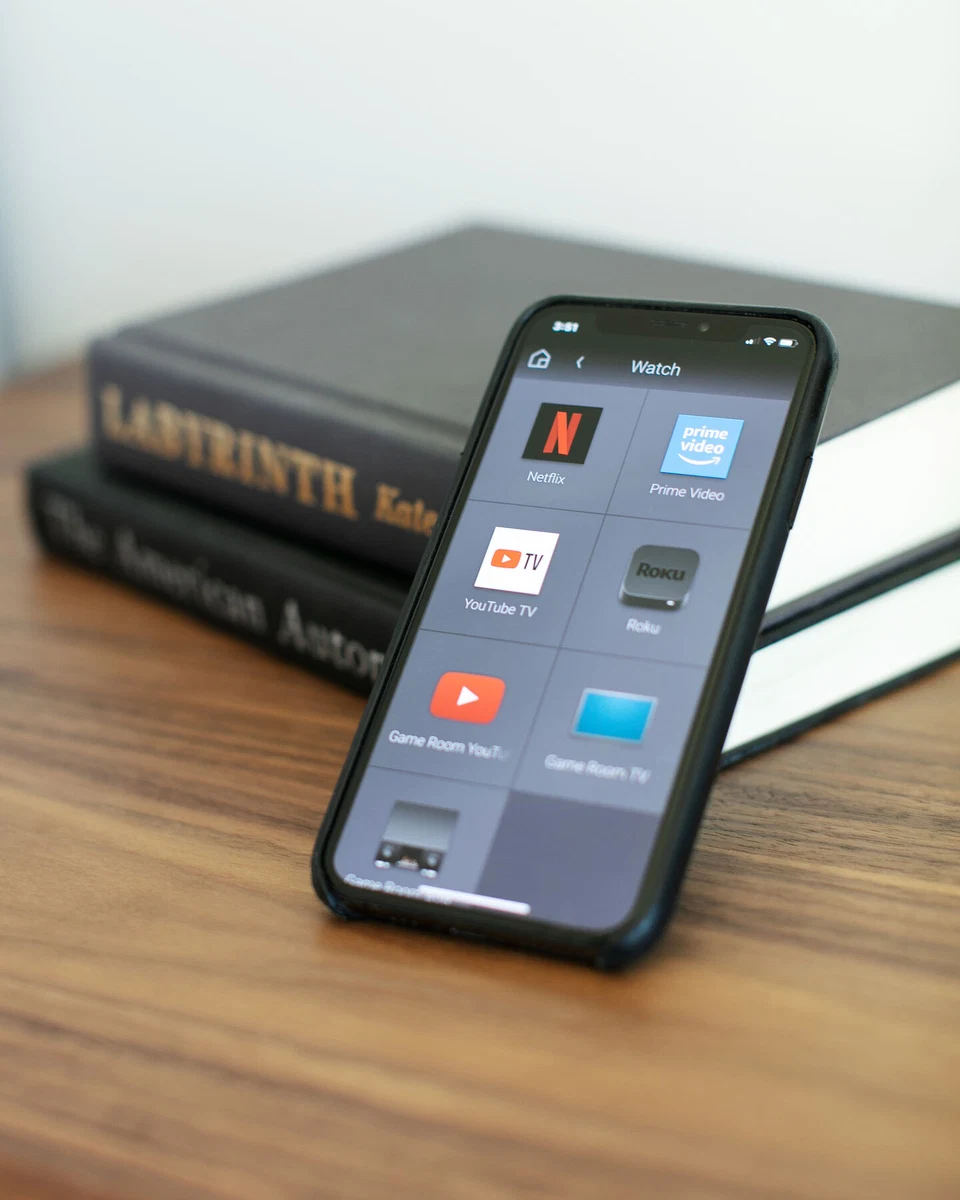 Close view of a smartphone home-control screen beside stacked books