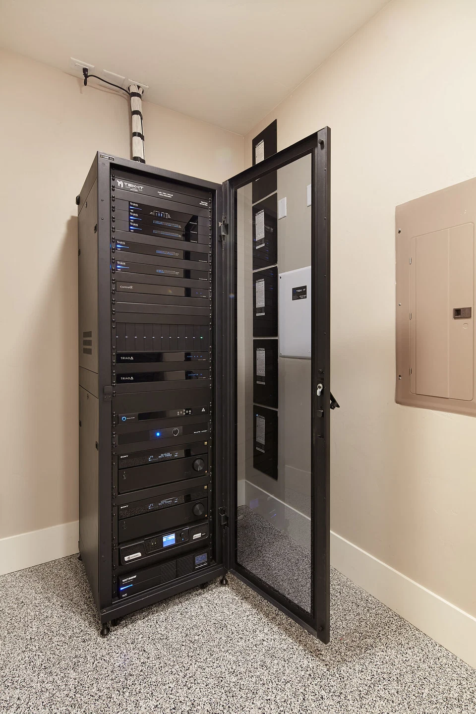 Open glass door revealing a recessed AV equipment rack