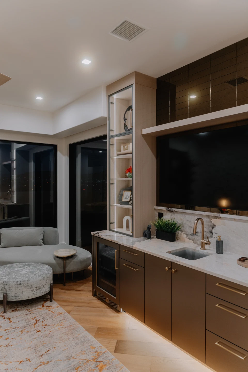 Built-in television above a countertop with illuminated wood cabinets