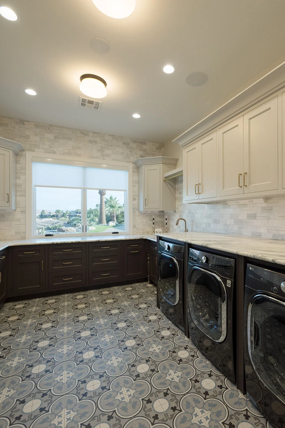 Laundry room with dark cabinetry, patterned floor tile, and recessed lighting
