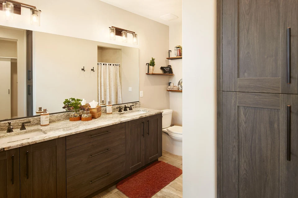 Bathroom vanity with a long mirror, recessed lighting, and dark wood cabinetry