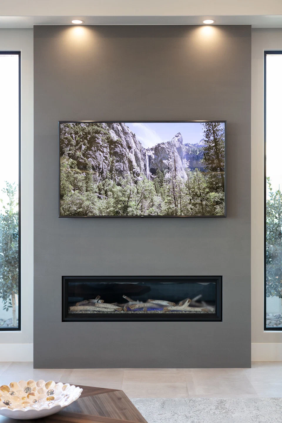 Television mounted above a linear fireplace on a dark accent wall
