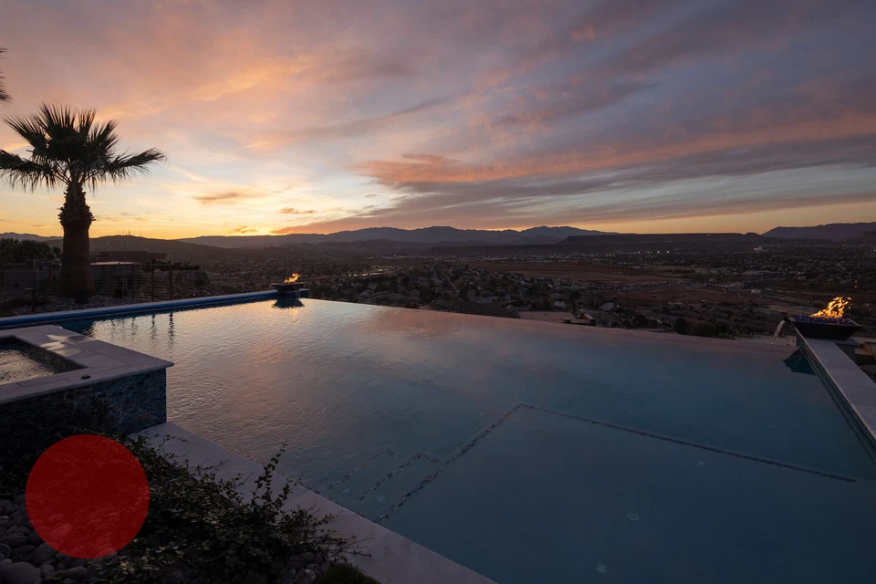 Infinity-edge pool reflecting sunset clouds above a desert valley