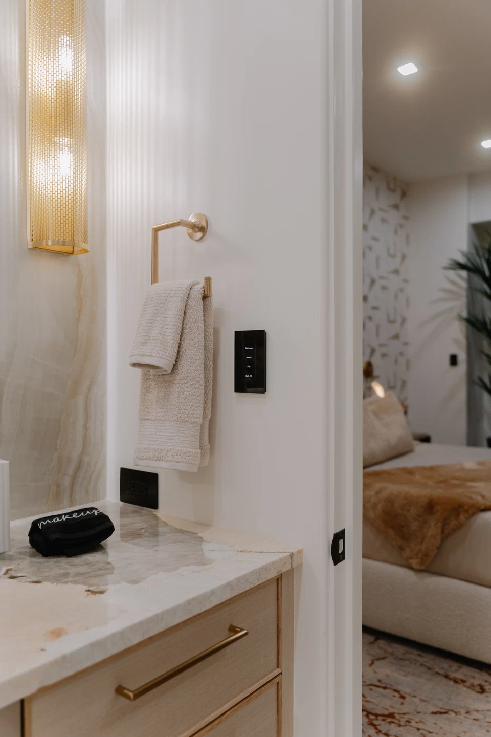 Bathroom wall keypad beside a towel rail and illuminated vanity