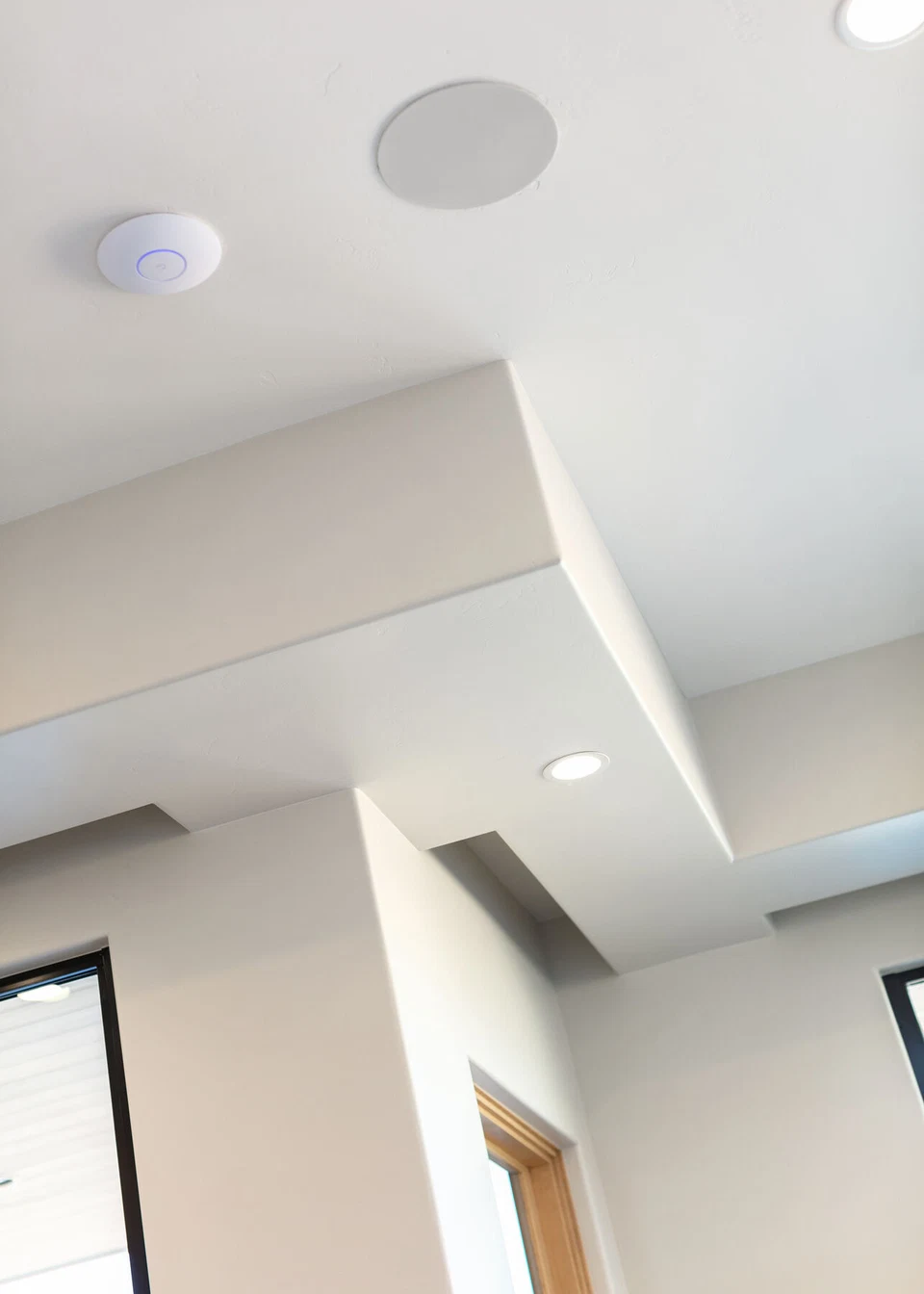 Round ceiling speaker and recessed lights above a white interior