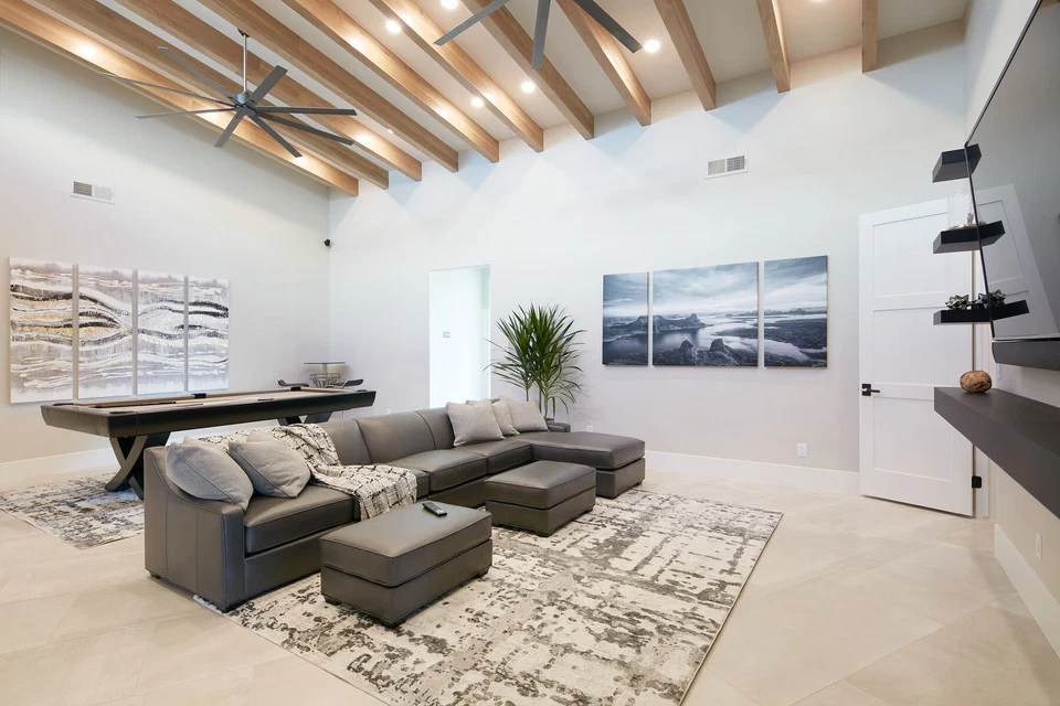 Media room with dark sectional sofa and wood ceiling beams
