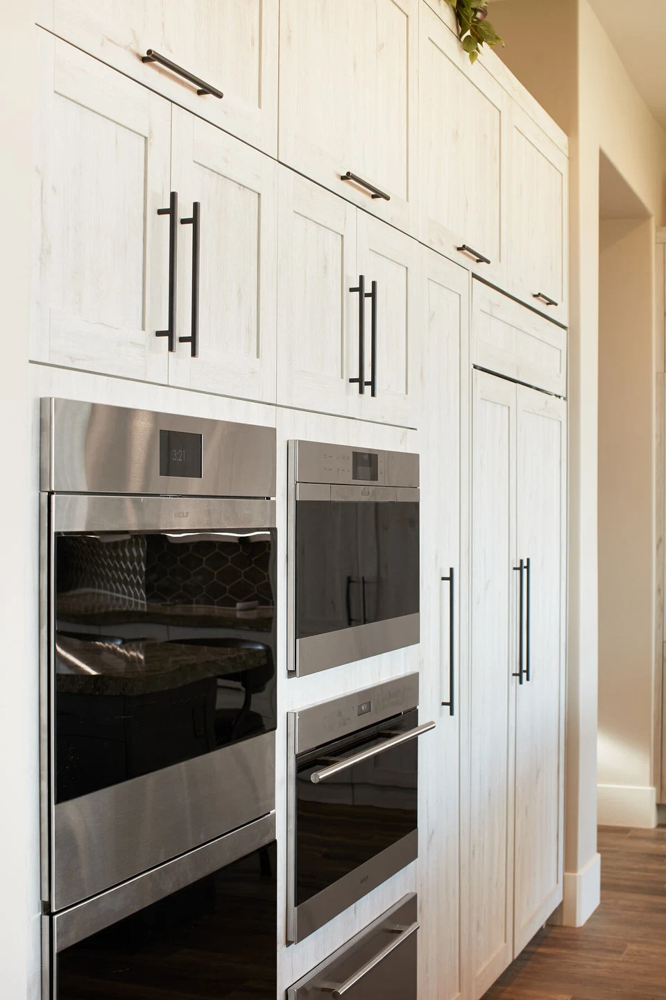 Built-in stainless steel ovens surrounded by white kitchen cabinets