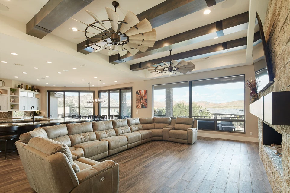 Living room sectional beneath wood ceiling beams and circular chandeliers