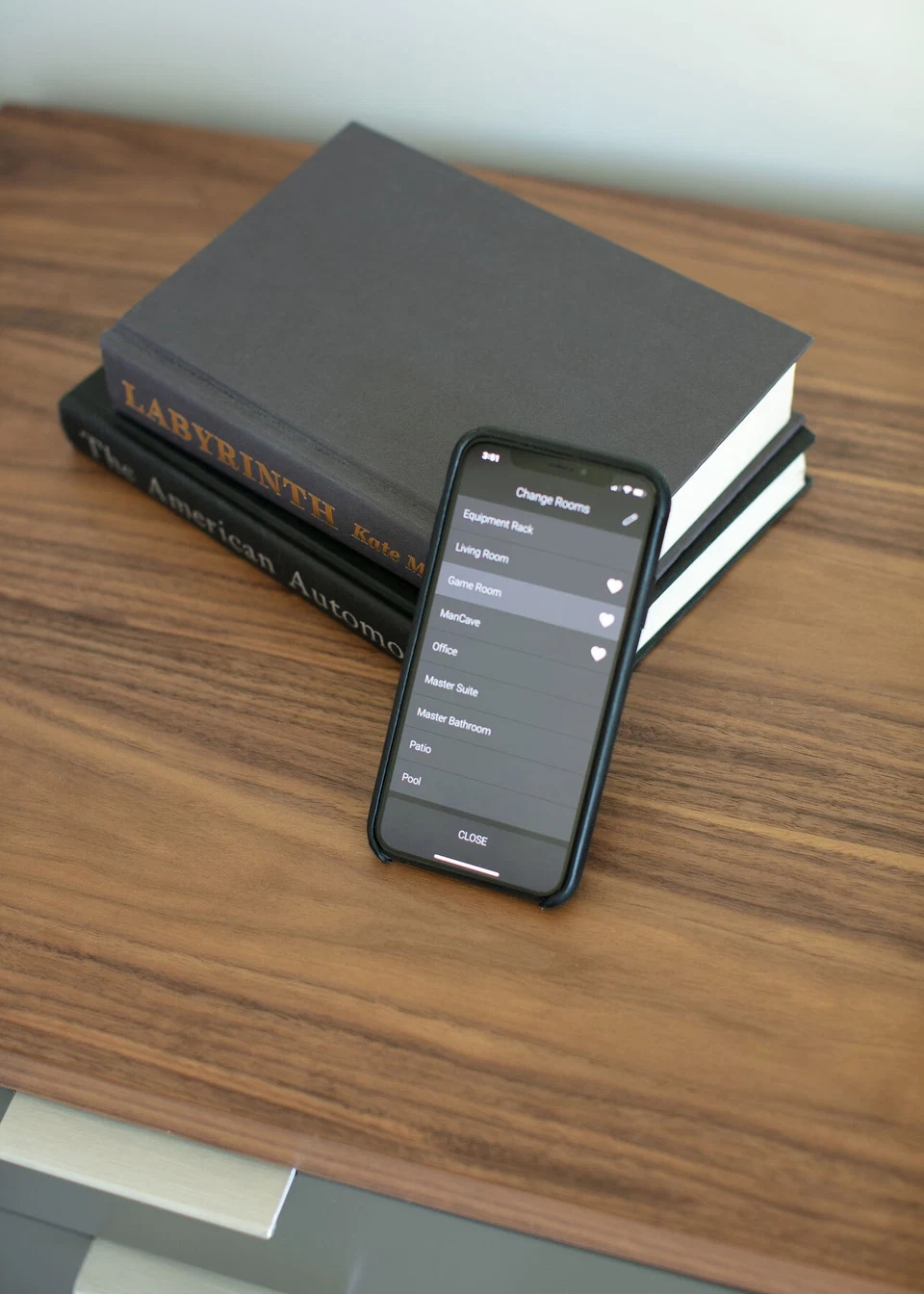 Smartphone displaying home controls while propped against books