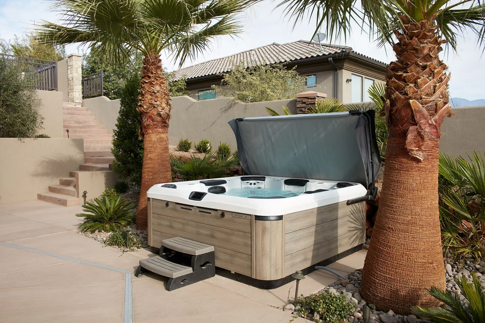 Outdoor hot tub between palm trees and a stucco wall